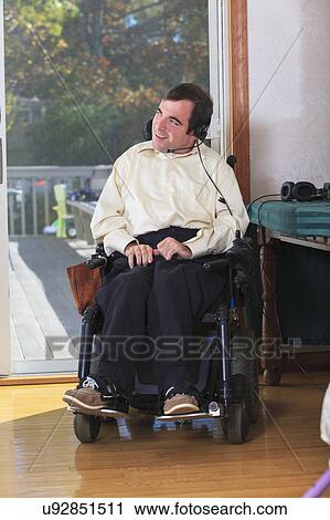 Stock Image - Man in wheelchair using hands free kit. Fotosearch