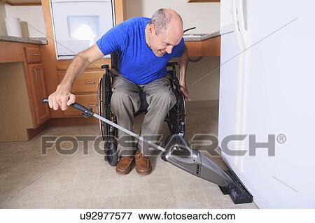 Man in wheelchair vacuuming his house View Large Photo Image Stock Photo - Man in wheelchair vacuuming his house. Fotosearch