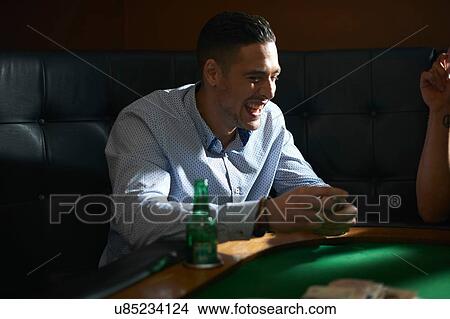Picture - Man shuffling playing cards at pub card table. Fotosearch