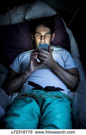 Man using smartphone in bed View Large Photo Image Stock Photo - Man using smartphone in bed. Fotosearch