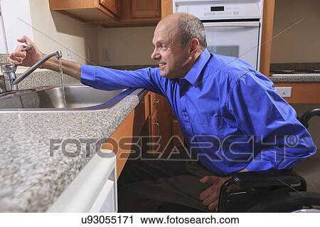 Stock Image - Man with deformed hands in the kitchen. Fotosearch