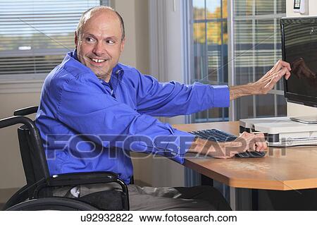 Stock Image - Man with deformed hands using a computer. Fotosearch