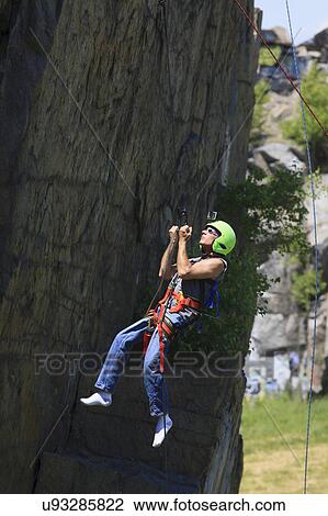 Stock Image - Man with spinal cord injury rock climbing. Fotosearch
