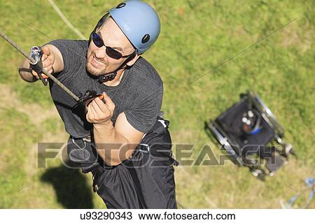 Stock Image - Man with spinal cord injury rock climbing. Fotosearch