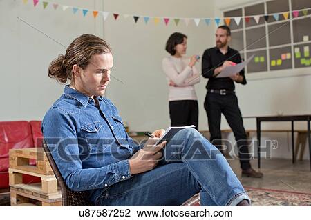 Man writing notes, colleagues in background View Large Photo Image Stock Image - Man writing notes, colleagues in background. Fotosearch