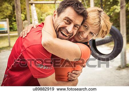 Stock Photo - Mature couple hugging looking at camera smiling. Fotosearch