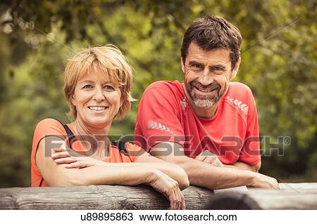 Mature couple leaning against log looking at camera smiling View Large Photo Image Stock Image - Mature couple leaning against log looking at camera smiling. Fotosearch