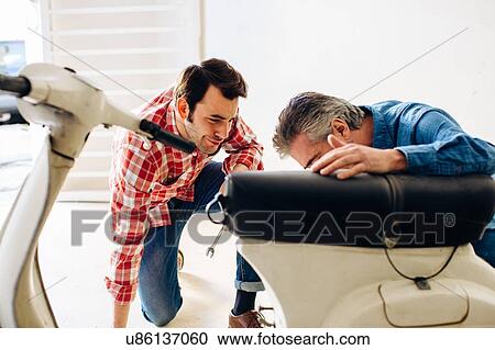 Mature man and adult son checking moped in garage View Large Photo Image Stock Image - Mature man and adult son checking moped in garage. Fotosearch