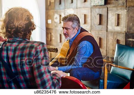 Mature man and adult son having guitar practice in living room View Large Photo Image Stock Photograph - Mature man and adult son having guitar practice in living room. Fotosearch
