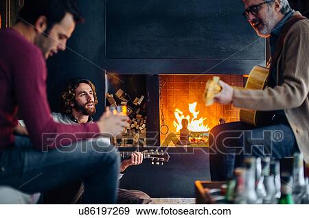 Mature man and adult sons playing guitars by living room fire View Large Photo Image Stock Photo - Mature man and adult sons playing guitars by living room fire. Fotosearch
