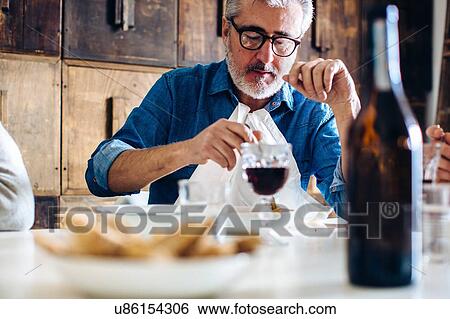 Stock Photograph - Mature man and sons eating at dining table. Fotosearch