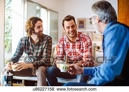 Mature man and two adult sons drinking coffee in living room View Large Photo Image Stock Photo - Mature man and two adult sons drinking coffee in living room. Fotosearch