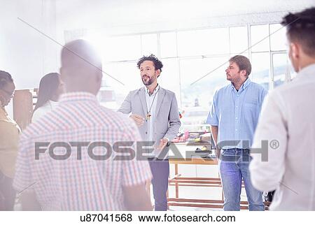 Stock Photo - Mature man in office speaking to colleagues. Fotosearch