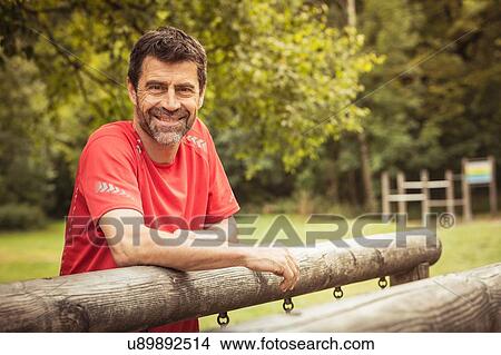 Mature man leaning against playground equipment looking at camera smiling View Large Photo Image Picture - Mature man leaning against playground equipment looking at camera smiling. Fotosearch