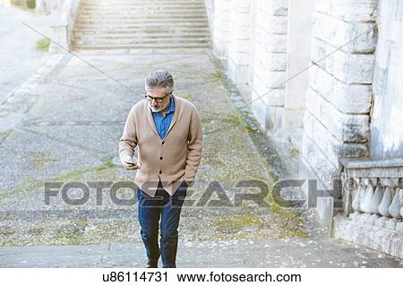 Mature man reading smartphone whilst moving up traditional stairway, Florence, Italy View Large Photo Image Stock Image - Mature man reading smartphone whilst moving up traditional stairway, Florence, Italy. Fotosearch
