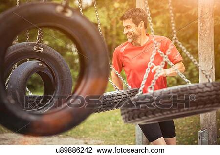 Mature man running by tyre swing looking away smiling View Large Photo Image Stock Image - Mature man running by tyre swing looking away smiling. Fotosearch
