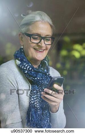 Mature woman smiling at message on smartphone View Large Photo Image Stock Image - Mature woman smiling at message on smartphone. Fotosearch