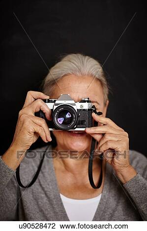 Stock Image - Mature woman taking photograph. Fotosearch
