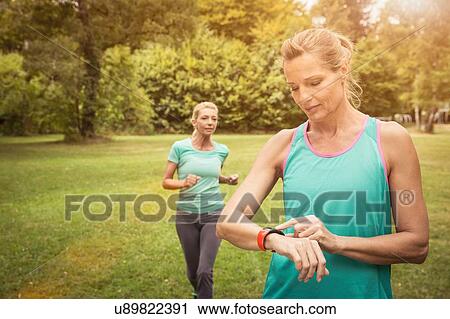 Mature women jogging in park, checking heart rate monitor wrist watch View Large Photo Image Stock Image - Mature women jogging in park, checking heart rate monitor wrist watch. Fotosearch