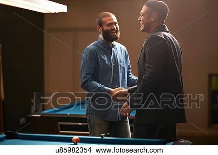 Picture - Men shaking hands at pool table. Fotosearch