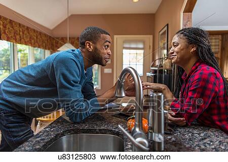 Mid adult couple chatting over kitchen counter View Large Photo Image Stock Image - Mid adult couple chatting over kitchen counter. Fotosearch
