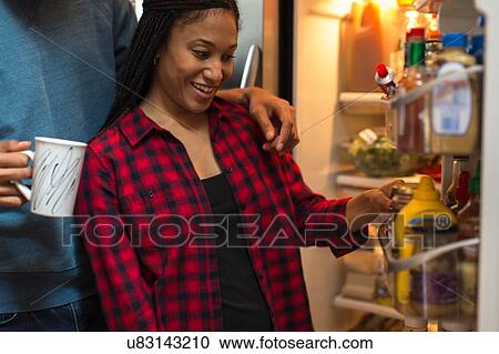 Mid adult couple choosing food from refrigerator in kitchen View Large Photo Image Stock Image - Mid adult couple choosing food from refrigerator in kitchen. Fotosearch