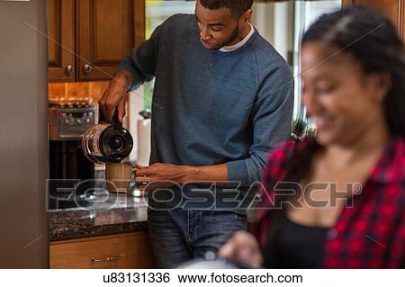 Mid adult couple pouring coffee in kitchen View Large Photo Image Stock Photograph - Mid adult couple pouring coffee in kitchen. Fotosearch