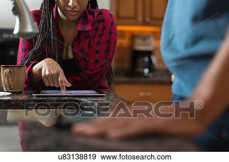 Mid adult couple using digital tablet at kitchen counter View Large Photo Image Stock Photo - Mid adult couple using digital tablet at kitchen counter. Fotosearch
