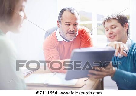 Mid adult man in office showing colleagues digital tablet View Large Photo Image Picture - Mid adult man in office showing colleagues digital tablet. Fotosearch