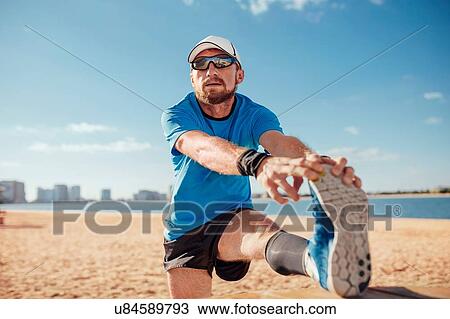 "Mid adult man on beach leg raised touching toes stretching foot, Dubai, United Arab Emirates" View Large Photo Image Stock Image - "Mid adult man on beach leg raised touching toes stretching foot, Dubai, United Arab Emirates". Fotosearch