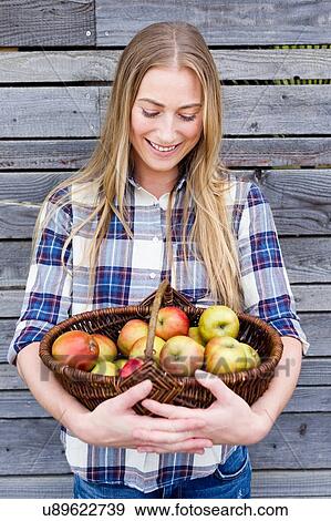 Stock Photo - Mid adult woman holding basket of homegrown apples. Fotosearch
