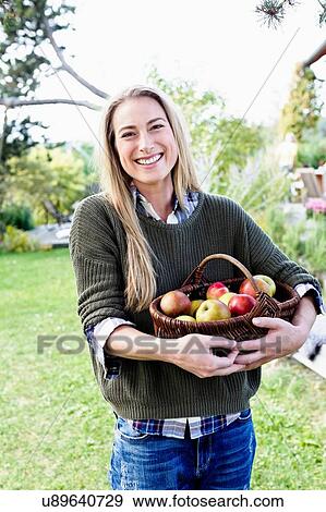 Mid adult woman holding basket of apples, portrait View Large Photo Image Stock Photo - Mid adult woman holding basket of apples, portrait. Fotosearch