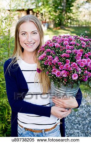 Stock Photography - Mid adult woman holding bucket with flowers. Fotosearch