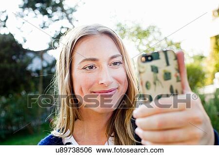 Stock Photograph - Mid adult woman holding smartphone. Fotosearch