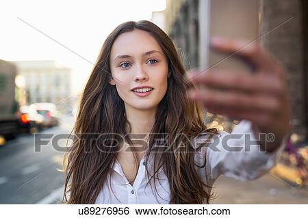 Mid adult woman on taking smartphone selfie on city street View Large Photo Image Stock Photograph - Mid adult woman on taking smartphone selfie on city street. Fotosearch