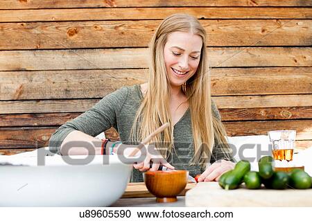 Mid adult woman preparing food at table outdoors View Large Photo Image Stock Image - Mid adult woman preparing food at table outdoors. Fotosearch