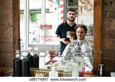 Stock Photo - Mirror image of barber using mirror to show smiling customer haircut. Fotosearch