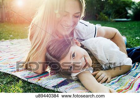 Picture - Mother and daughter lying on rug in garden. Fotosearch