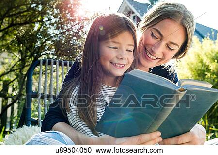 Stock Image - Mother and daughter reading book. Fotosearch