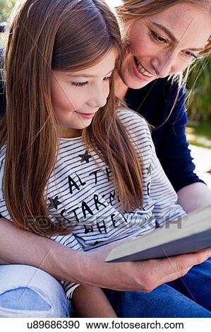 Mother and daughter reading book together, smiling View Large Photo Image Stock Image - Mother and daughter reading book together, smiling. Fotosearch