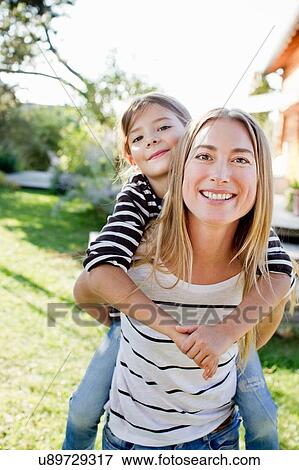 Stock Photo - Mother giving daughter piggy back. Fotosearch