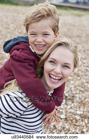 Picture - Mother giving son piggy back. Fotosearch