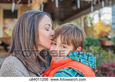 Mother hugging and kissing son in front of house View Large Photo Image Stock Photograph - Mother hugging and kissing son in front of house. Fotosearch