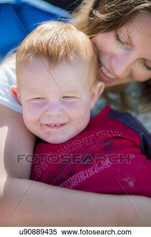 Stock Photography - Mother hugging toddler with red hair. Fotosearch