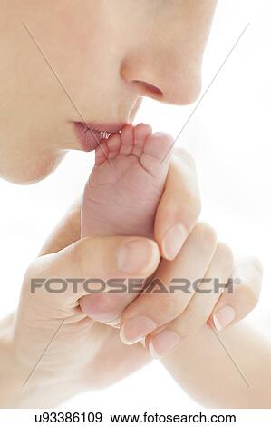 Stock Photo - Mother kissing newborn's foot. Fotosearch