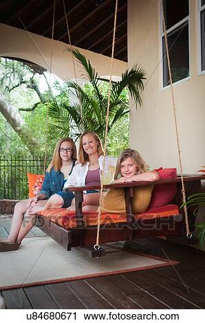 "Mother with daughters, sitting on porch swing looking at camera smiling" View Large Photo Image Stock Image - "Mother with daughters, sitting on porch swing looking at camera smiling". Fotosearch