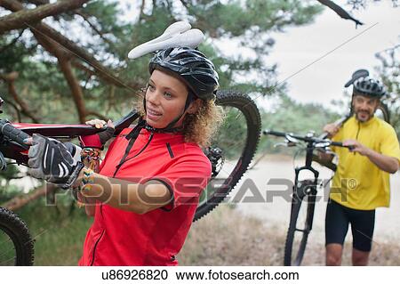 Mountain biking couple carrying cycles over sand on riverbank View Large Photo Image Stock Image - Mountain biking couple carrying cycles over sand on riverbank. Fotosearch