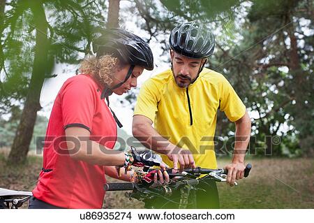 Mountain biking couple checking cycle handlebar in forest View Large Photo Image Picture - Mountain biking couple checking cycle handlebar in forest. Fotosearch