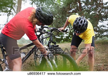 Mountain biking couple checking cycle wheel in forest View Large Photo Image Stock Photo - Mountain biking couple checking cycle wheel in forest. Fotosearch