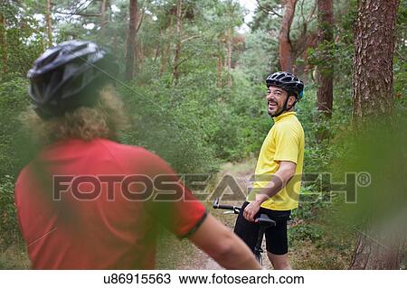 Stock Image - Mountain biking couple taking a break on forest trail. Fotosearch